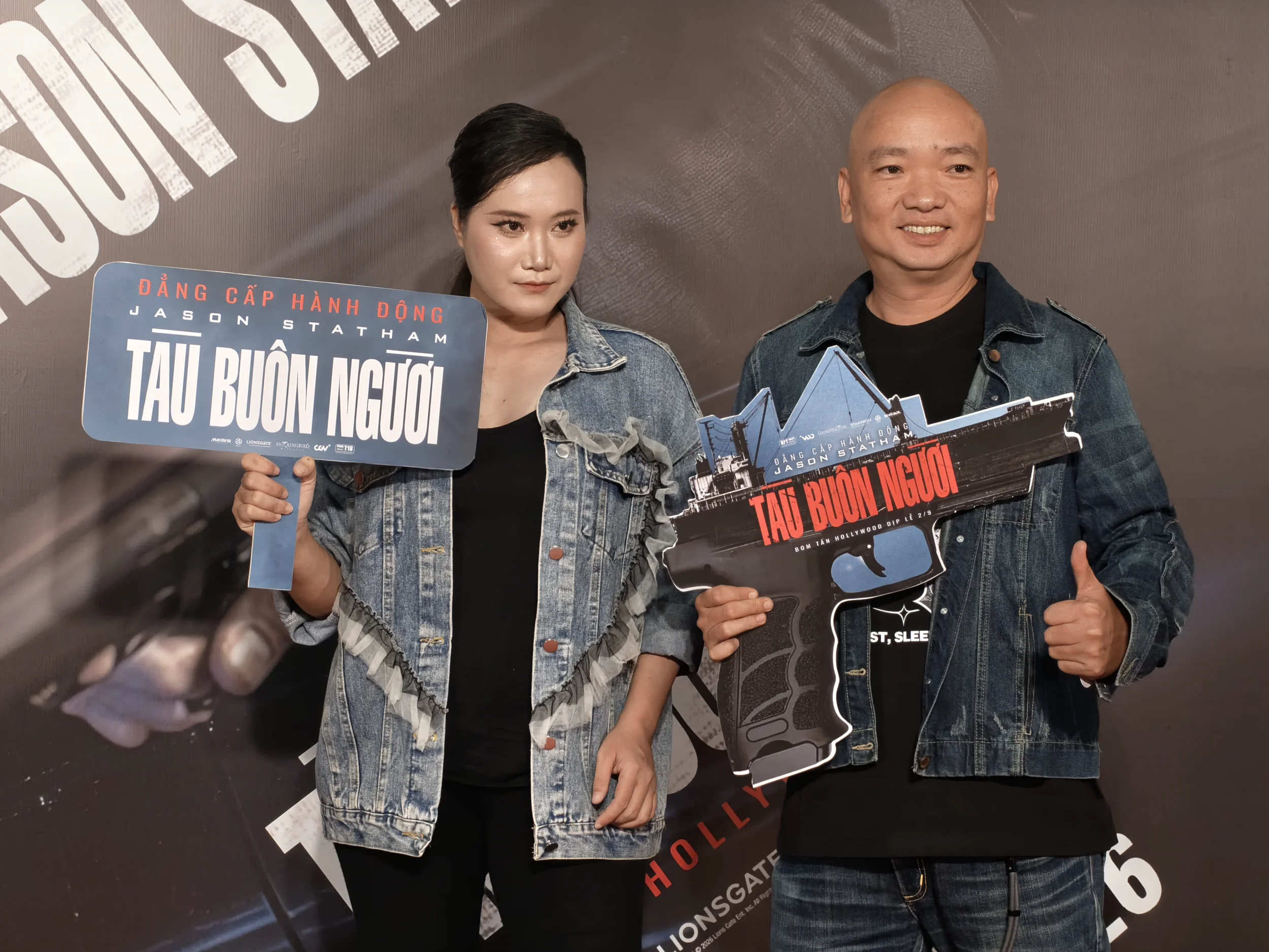 Khách mời pose với prop súng và standee phim