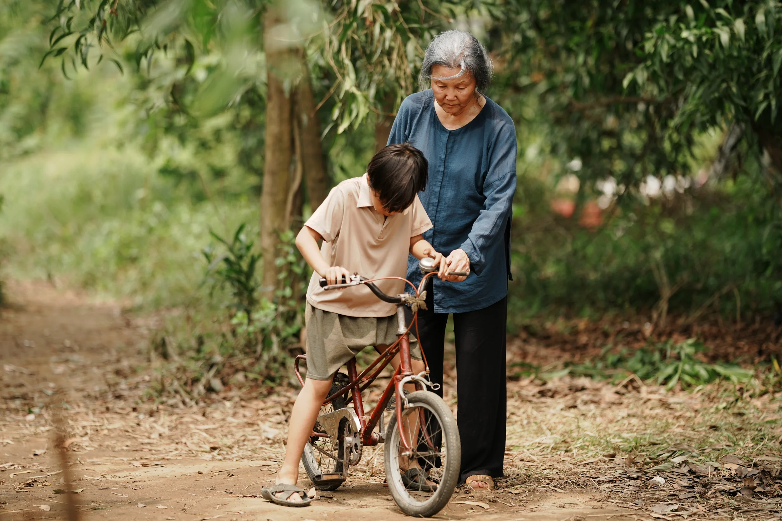 Bà dạy cháu đi xe đạp trên đường quê